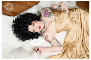 Portrait of Margaret Cho, star of the comedy concert film CHO DEPENDENT, with tattoos, elegant gown, lying on a a white lambskin