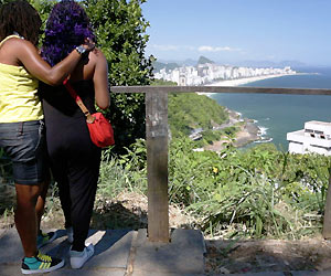 Film Still FAVELA GAY (NRW-Premiere) von Rodrigo Felha; ein lesbisches Pärchen steht über dem Strand-Panorama von Rio de Janeiro
