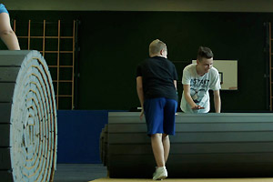 Film Still JENSEITS VON ROSA UND HELLBLAU von Marcus Gerhard Preis; der transsexuelle Nuka rollt mit Mitschüler eine Matte in der Sporthalle auf