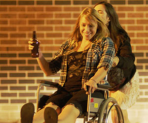 Film Still SKIN DEEP von Jon Leahy; Leah (gespielt von Zara Zoe) schiebt eine lachende Caitlin (gespielt von Monica Zanetti) in einem Rollstuhl durch die Nacht