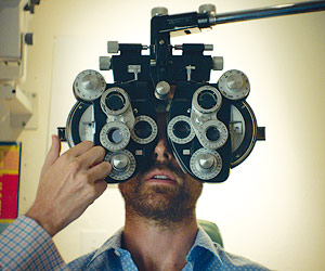 Film Still AUF DEN ZWEITEN BLICK – LAZY EYE von Tim Kirkman mit Lucas Near-Verbrugghe und Aaron Costa Ganis; Hauptcharakter Dean sitzt beim Augenarzt und bekommt seine Augen vermessen.