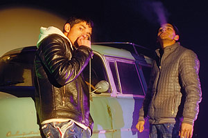 Film Still BRÜDER DER NACHT von Patric Chiha; zwei junge Roma rauchen nachts vor einem grünen Auto