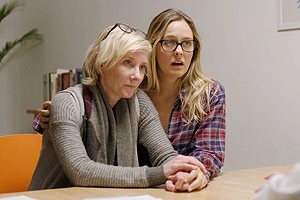 Film Still CATFIGHT von Onur Tukel; mit Sandra Oh, Tituss Burgess, Catherine Curtin; das lesbische Pärchen Ashley und Lisa (gespielt von Anne Heche, Alicia Silverstone) sitzen beim Arzt und halten Händchen