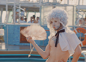 Film Still DREAM BOAT von Tristan Ferland Milewski; Berlinale-Dokumentarfilm über eine schwule Kreuzfahrt; Passagier an Deck in Rococo-Drag-Kostüm mit Fächer