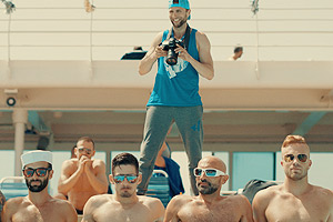 Film Still DREAM BOAT von Tristan Ferland Milewski; Berlinale-Dokumentarfilm über eine schwule Kreuzfahrt; vier sexy Kerle sitzen mit Sonnenbrillen nebeneinander und ein Fotograf steht hinter ihnen