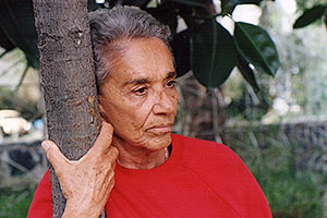 Film Still CHAVELA von Catherine Gund und Daresha Kyi über die lateinamerikanische Ranchera-Sängerin Chavela Vargas mit Pedro Almodóvar; Chavela lehnt sich mit einem einem roten Pullover an einen Baumstamm