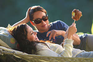 Film Still MILLIONEN MOMENTE VOLLER GLÜCK – A MILLION HAPPY NOWS von Albert Alarr; Lainey Allen (gespielt von Crystal Chappell) beobachtet, wie ihre Lebenspartnerin Eva Morales (gespielt von Jessica Leccia) in der Hängematte einen Schoko-Apfel isst