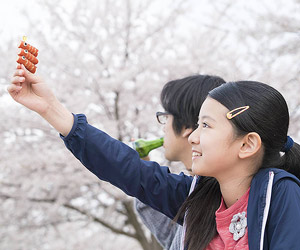 Film Still CLOSE-KNIT – Karera ga Honki de Amu toki wa von Naoko Ogigami mit Tôma Ikuta, Eiko Koike, Kenta Kiritani und Rin Kakihara; die 11-jährige Tomo (gespielt von Rin Kakihara) und ihr Onkels Makio (gespielt von Kenta Kiritani) machen ein Picknick unter japanischen Kirschblüten