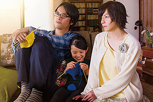 Film Still CLOSE-KNIT – Karera ga Honki de Amu toki wa von Naoko Ogigami mit Tôma Ikuta, Eiko Koike, Kenta Kiritani und Rin Kakihara; die 11-jährige Tomo (gespielt von Rin Kakihara) sitzt strickend zwischen ihrem Onkel Makio (gespielt von Kenta Kiritani) und dessen Freundin Rinko (Tôma Ikuta)