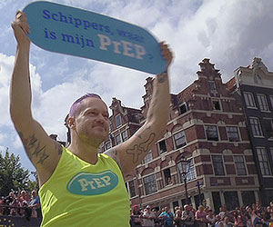Film Still PrEP&ME von Tim Dekkers; ein Teilnehmer einer Teststudie des neuen HIV-Vorsorgemedikaments PrEP hält beim Canal Pride in Amsterdam eine Schild hoch