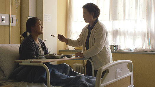 Film Still aus dem Kurzfilm FIRST LOVE von Ji-Sook Kang, Teil der Kurzfilmsammlung SMALL PALE BLUE GIRLS; eine koreanische Frau versucht ihrer geliebten Freundin, die im Krankenhaus liegt, Essen zu reichen