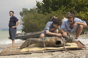 Film Still CALL ME BY YOUR NAME von Regisseur Luca Guadagnino; Elio Perlman (gespielt von Timothée Chalamet) begutachtet mit Oliver (gespielt von Armie Hammer) eine Statue, während Elios Vater (gespielt von Michael Stuhlbarg) am Seestrand steht