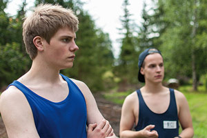 Film Still PIHALLA – SCREWED – AUF ZU NEUEN UFERN von Regisseur Nils-Erik Ekblom; der 17-jährige Miku (gespielt von Mikko Kauppila) und sein Freund Elias (gespielt von Valtteri Lehtinen) stehen mit Sport-Hemden im Wald