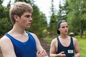 PIHALLA – AUF ZU NEUEN UFERN Film Still PIHALLA – SCREWED – AUF ZU NEUEN UFERN von Regisseur Nils-Erik Ekblom; der 17-jährige Miku (gespielt von Mikko Kauppila) und sein Freund Elias (gespielt von Valtteri Lehtinen) stehen mit Sport-Hemden im Wald