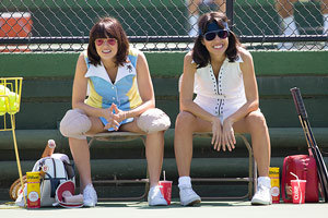 Film Still BATTLE OF THE SEXES – GEGEN JEDE REGEL von den Regisseuren Jonathan Dayton & Valerie Faris mit Steve Carell, Bill Pullman, Alan Cumming, Elisabeth Shue und Sarah Silverman; Wimbledon-Ikone Billie Jean King (gespielt von Emma Stone) sitzt mit Sonnenbrille auf einem Tennisplatz neben der Spielerin Rosie Casals (gespielt von Natalie Morales)