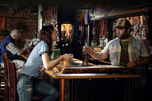 Film Still BECKS von den Regisseuren und Ko-Autoren Daniel Powell und Elizabeth Rohrbaugh mit Christine Lahti, Mena Suvari und Sängerin Hayley Kiyoko; Rebecca (gespielt von Lena Hall) steht am Tresen von Barbetreiber Dave (gespielt von Dan Fogler)
