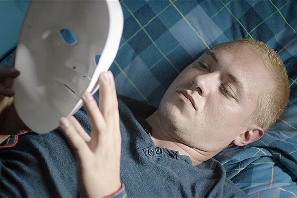 Film Still JAHR DES TIGERS – THE YEAR I LOST MY MIND, ein queerer Berlin-Thriller von Tor Iben mit Julien Lickert, Patrick G. Boll, Michael del Coco und Christian Harting; der verkappt schwule Dieb Tom (gespielt von Alexander Tsypilev) liegt auf einem Bett und hält eine weiße Plastik-Maske hoch