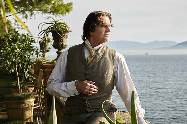 Film Still THE HAPPY PRINCE, Regiedebüt von Rupert Everett mit Colin Firth, Emily Watson, Tom Wilkinson und Béatrice Dalle; der schwule Autor und Dandy Oscar Wilde (gespielt von Everett) steht vor einem üppig grünen Garten an einem Bergsee
