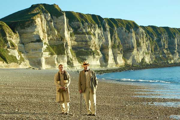 Film Still THE HAPPY PRINCE, Regiedebüt von Rupert Everett mit Colin Firth, Emily Watson, Tom Wilkinson und Béatrice Dalle; der schwule Autor und Dandy Oscar Wilde (gespielt von Everett) und sein Geliebter Robbie Ross (gespielt von Edwin Thomas) gehen einen Strand vor einer Felsenküste entlang