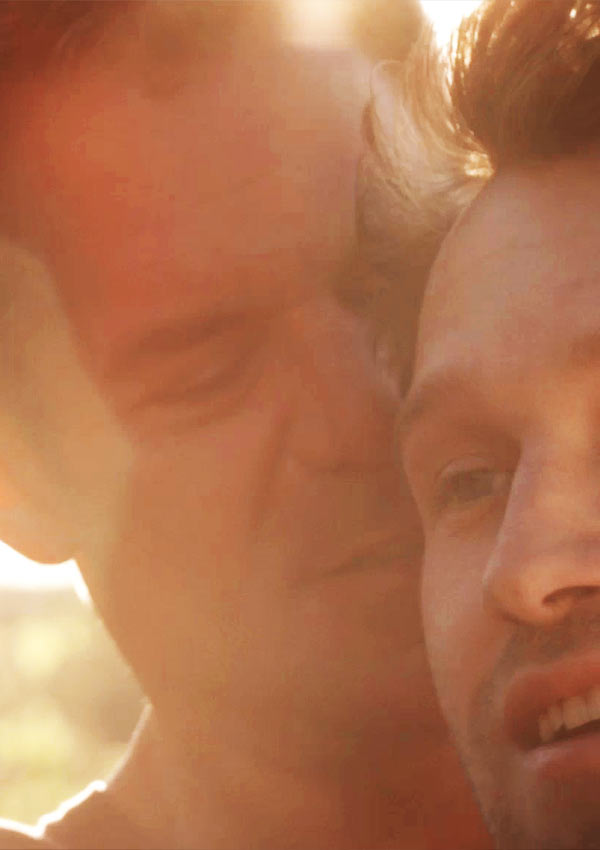 RETAKE Film Still RETAKE von Regisseur und Autor Nick Corporon mit Devon Graye, Derek Phillips und Chris Pudlo; Jonathan (gespielt von Tuc Watkins) steht im Sonnenschein hinter seinem schwulen Lover