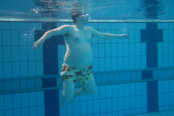 Film Still A DEAL WITH THE UNIVERSE vom transsexuellen Filmemacher Jason Barker aus England, 2018; Unterwasseransicht von Jason Barker mit einem Babybauch in einem Schwimmbecken
