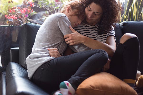 Film Still EVA + CANDELA von Autorin, Regisseurin und ausführender Produzentin Ruth Caudeli aus Kolumbien, 2018; Eva (gespielt von Silvia Varón) schmiegt sich Trost suchend auf dem Sofa an die Schulter Candela (Alejandra Lara)