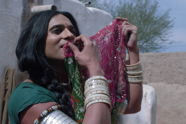 Film Still KHEJDI von Debüt-Regisseur Rohit Dwivedi aus Indien, 2018, mit Hindi-TV-Star Ashish Sharma; Khejdi (gespielt von Sharma) hält im sonnigen Hof den Saum ihres Saris an den Mund mit vielen Armreifen