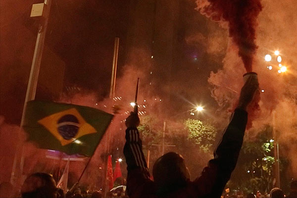 Film Still OBSCURO BARROCO von Regisseurin Evangelia Kranioti, eine französisch-griechische Doku über den Straßenkarneval von Rio de Janeiro; Feiernde schwenken nachts die brasilianische Flagge und versprühen bunten Nebel