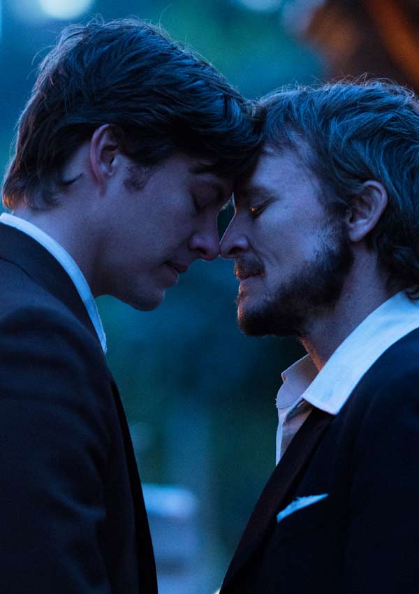 Film Still RIOT von Regisseur Jeffrey Walker aus AUS, 2018, über Homo-Aufstände zum ersten Mardi Gras in Australien; Lance Gowland (gespielt von Damon Herriman) und Jim Walker (gespielt von Xavier Samuel) stehen in Anzug vertraut Stirn an Stirn