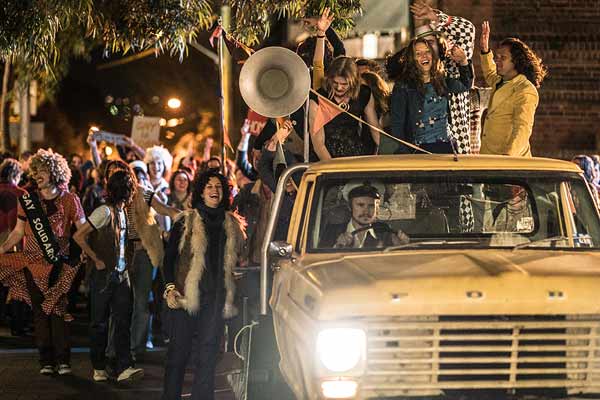 Film Still RIOT von Regisseur Jeffrey Walker aus AUS, 2018, über Homo-Aufstände zum ersten Mardi Gras in Australien; Lance Gowland (gespielt von Damon Herriman) fährt einen Pick-up-Truck mit feiernden und protestierenden Menschen auf der Ladefläche