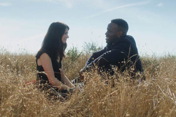 Film Still THE DEEP SKY von Regisseur, Autor, Produzent und Kameramann Frazer Bradshaw aus USA, 2017; Lenora (gespielt von Sarah Rose Butler) und ihr Partner Arlan (gespielt von Kelechi Nwadibia) sitzen zusammen in einer strohigen Wiese